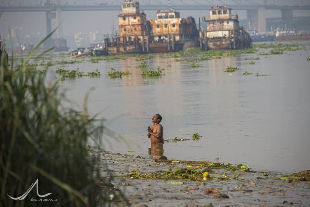A man makes his morning prayers in the waters of the Hooghly (Ganges) River near Fairley Ghat, Calcutta, India.