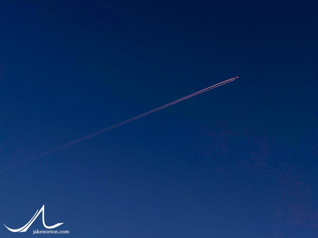 A plane and contrail streak across the evening sky high above Colorado. Destination unknown.