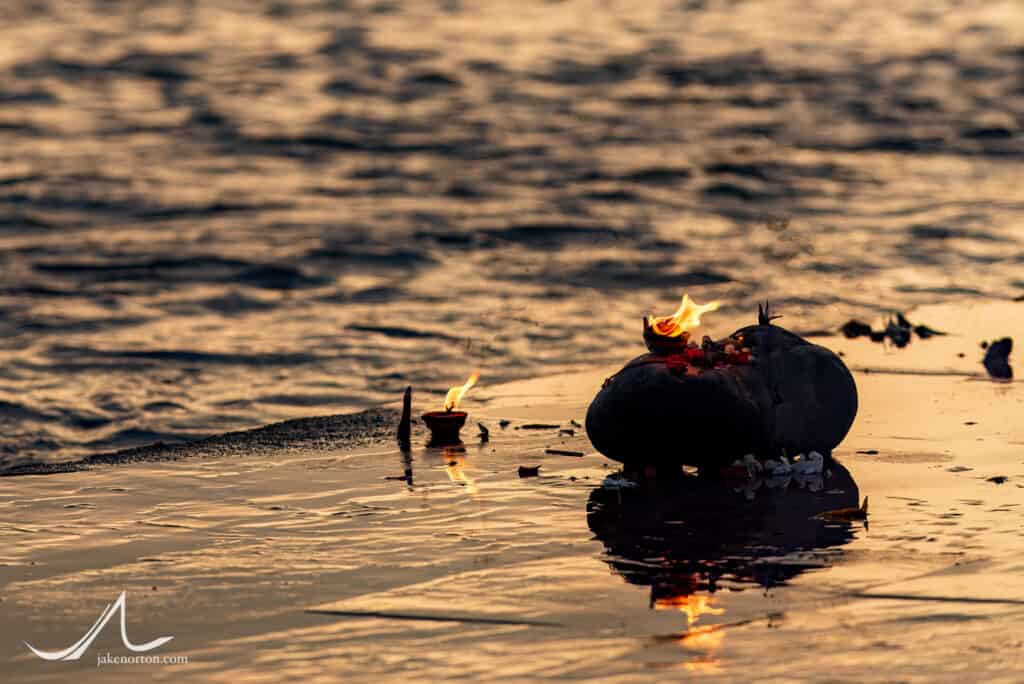 Sacred butter lamps burn on the shores of the Ganges River at Triveni Ghat, Rishikesh, India.