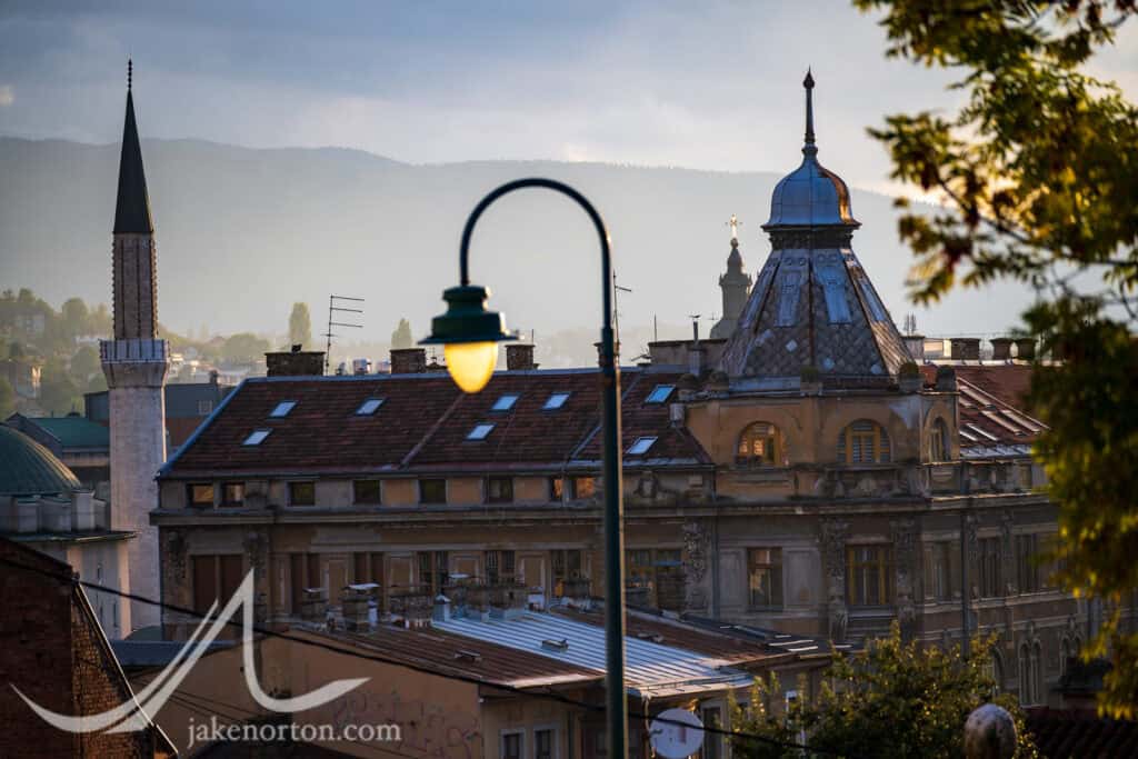 Minaret, Orthodox cross, and Habsburg rooftop: three empires and faiths in a single Sarajevo skyline.